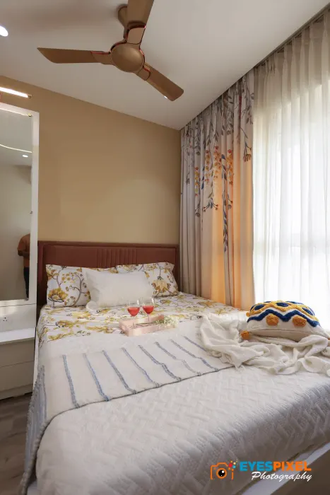 Apartment bedroom with sheer curtains, a mirrored wardrobe and a made bed