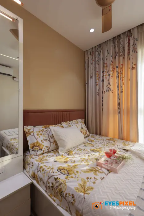 Mirrored wardrobe reflecting the bed and window of a compact apartment bedroom