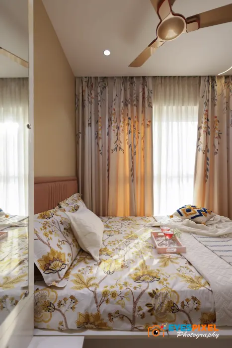 Bedroom window with layered curtains and a printed bedspread below it