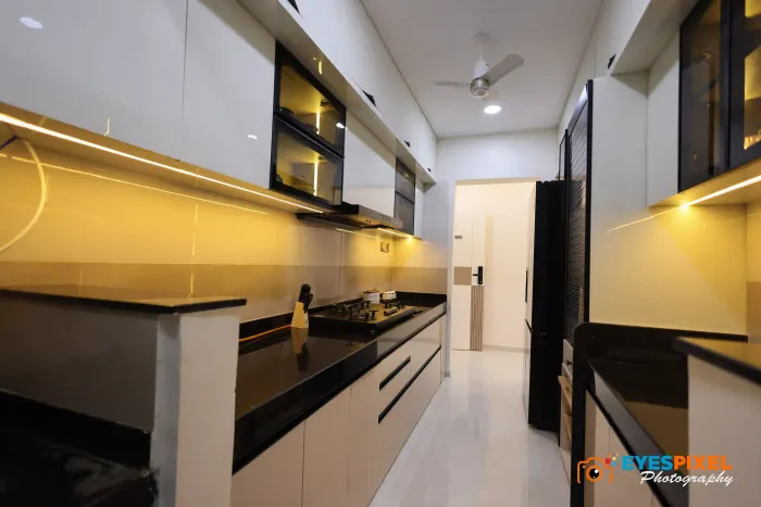 Modular kitchen with a black counter, gloss cabinets and lit backsplash