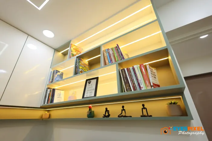 Lit bookshelf holding books, framed certificates and small figures