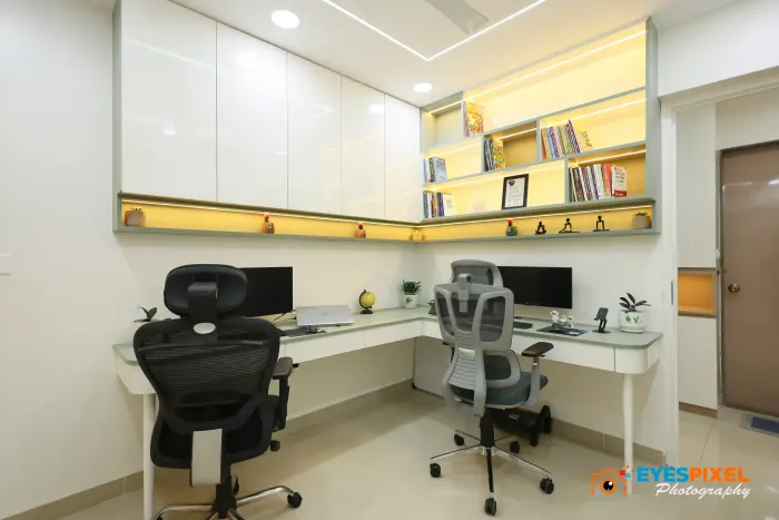 Study room with two workstations, task chairs and a lit bookshelf above