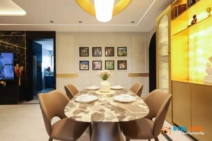 Dining room with a round marble table, six upholstered chairs and a lit display unit