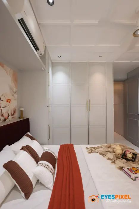 Guest bedroom with white fitted wardrobes and an air conditioner above the bed
