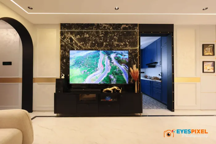 Living room television unit set against a black marble panel with a blue kitchen beyond