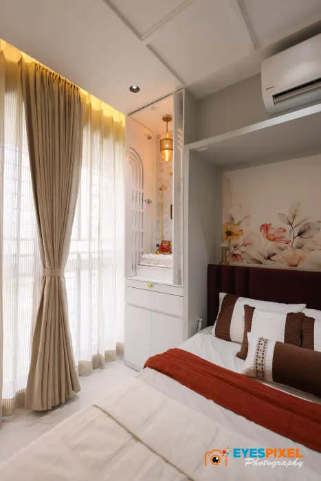 Master bedroom with a fitted wardrobe, floor-length curtains and a red bed runner in a Pune home
