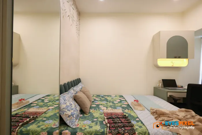 Bedroom with a green printed bedspread, fluted headboard and a work desk
