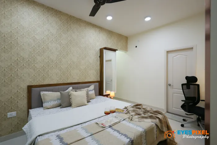 Bedroom with a textured wallpaper wall, task chair and bedside lamp