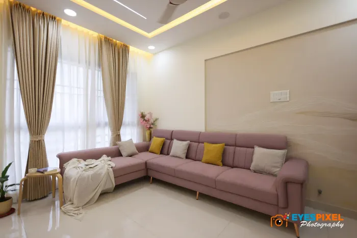 Pink L-shaped sofa below a curtained window in a living room