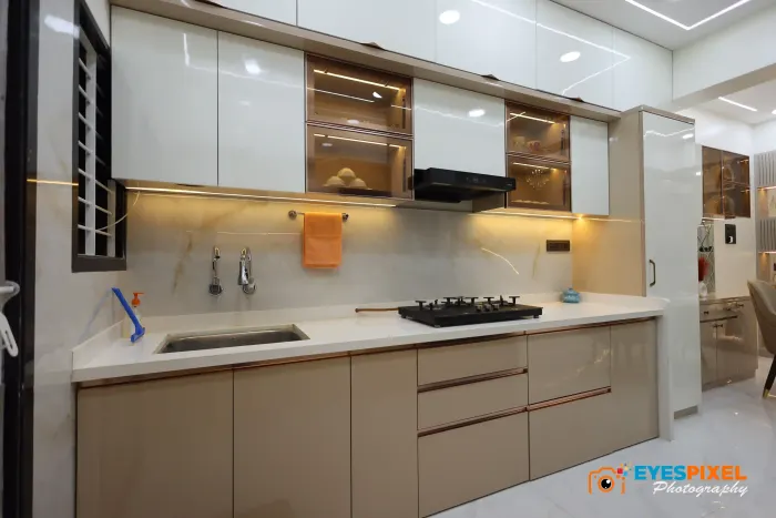 Kitchen with gloss cabinets, a white counter and a lit backsplash