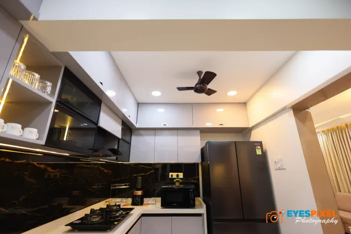 Wide view of a kitchen with a black marble backsplash and integrated appliances