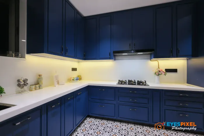 Navy kitchen counter with a hob, lit backsplash and overhead cabinets