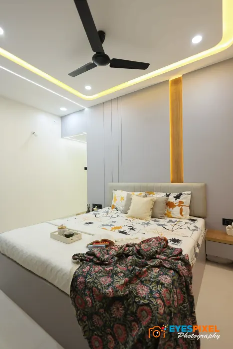 Bedroom with a printed bedspread, ceiling fan and a curved light cove
