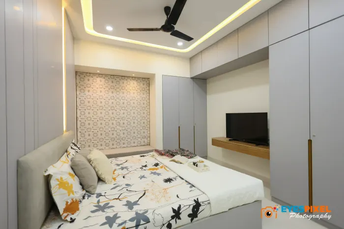 Bedroom with a wall-mounted television on a wooden ledge opposite the bed