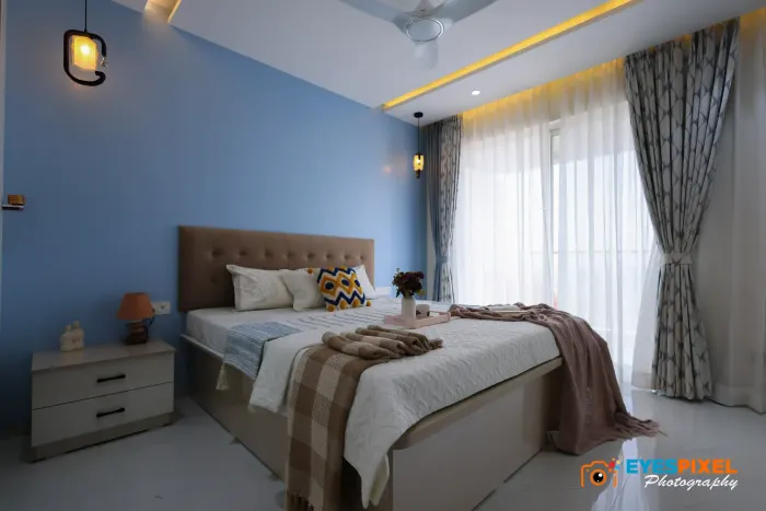 Bedroom with a blue feature wall, tufted headboard and sheer layered curtains