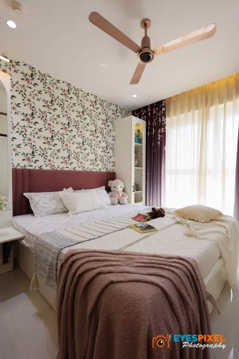 Bedroom with floral wallpaper behind a wine-red upholstered headboard