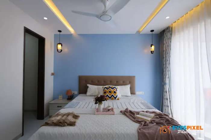 Wide view of a blue bedroom with pendant lights either side of the bed