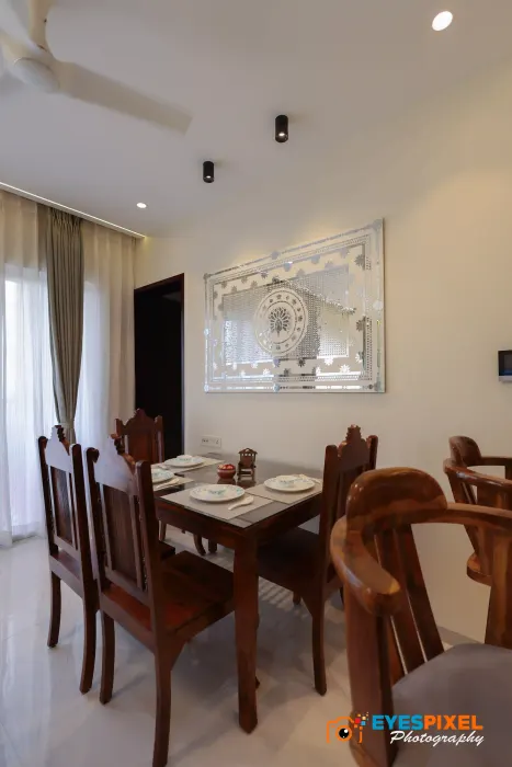 Wooden dining table and chairs set below a carved wall mirror