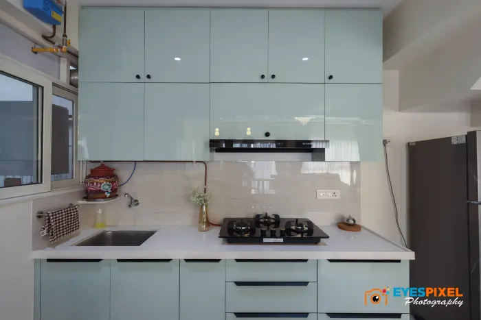 Mint-green modular kitchen with a white counter and a window above the sink