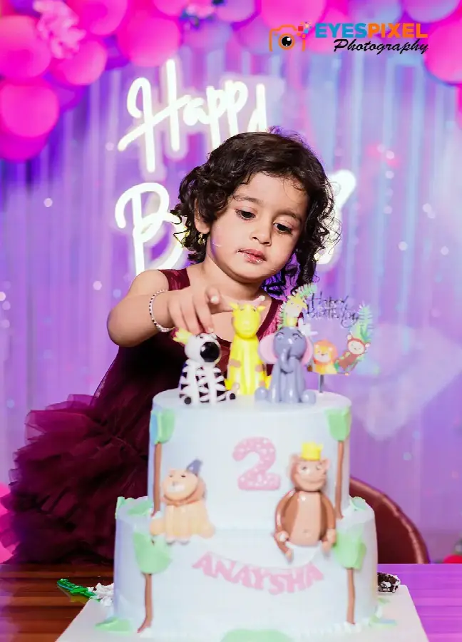 Two-year-old reaching for the animal toppers on her jungle-themed birthday cake