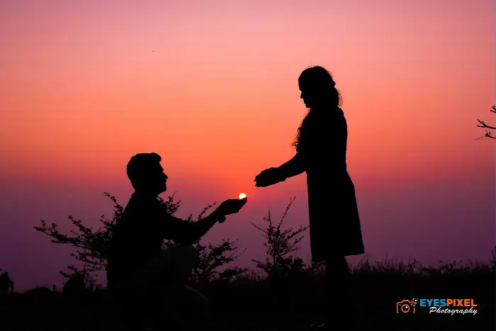 Silhouette of a man on one knee proposing at sunset, the sun held between their hands