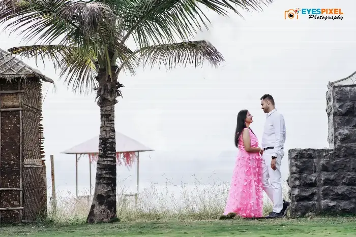 Couple facing each other beside a palm tree on a misty lakeside lawn