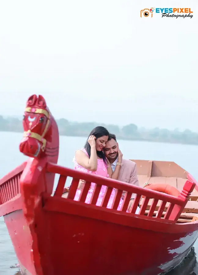 Couple laughing together in a red horse-headed boat on still water