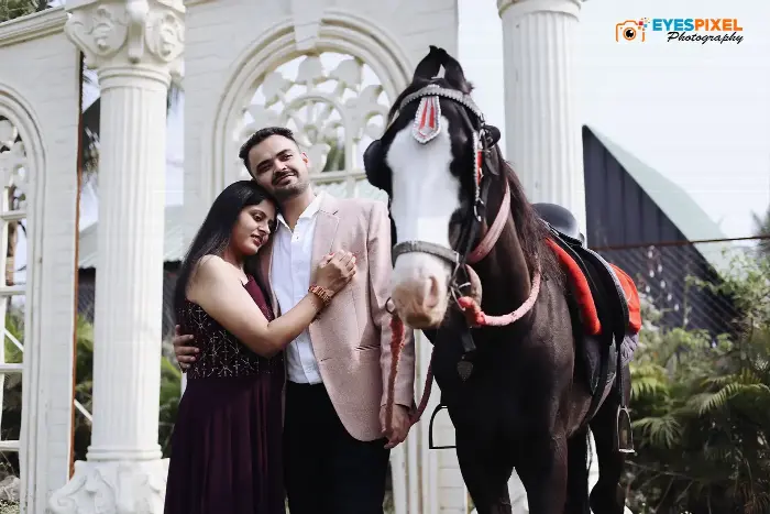Couple standing beside a decorated horse in front of a white pillared venue