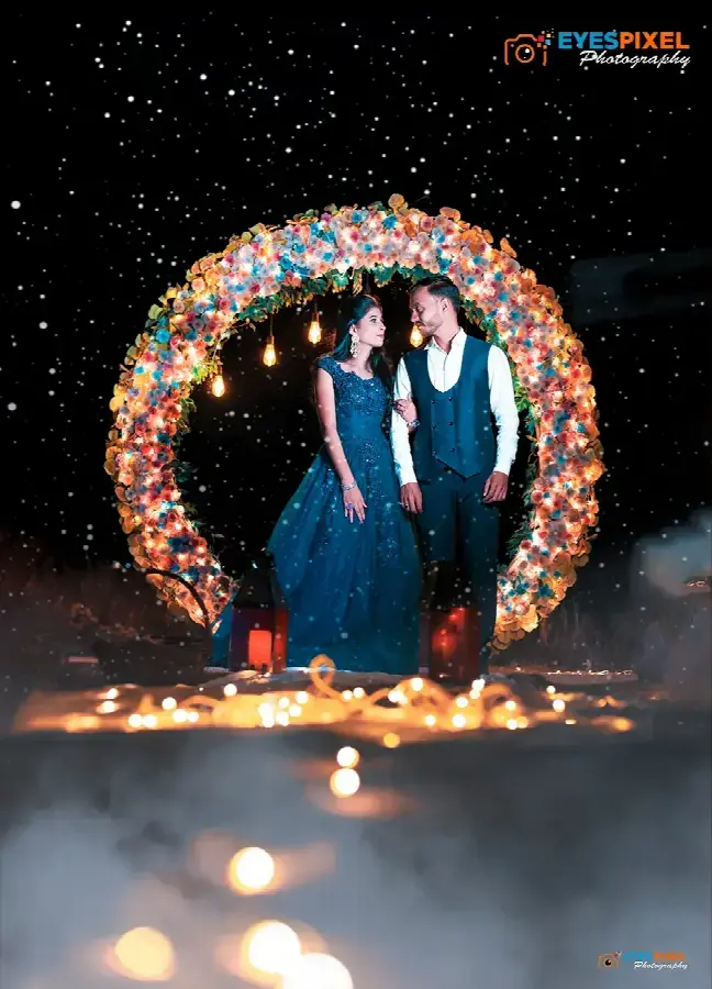Couple standing inside a lit floral arch at night, candles and mist around them