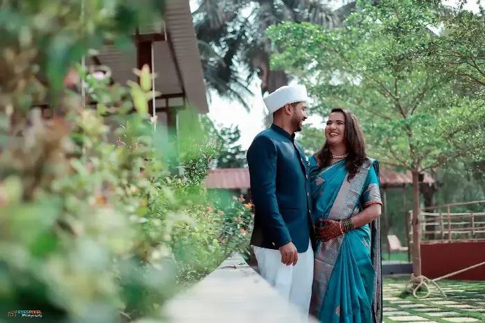 Couple in traditional Maharashtrian dress laughing together in a garden at their wedding