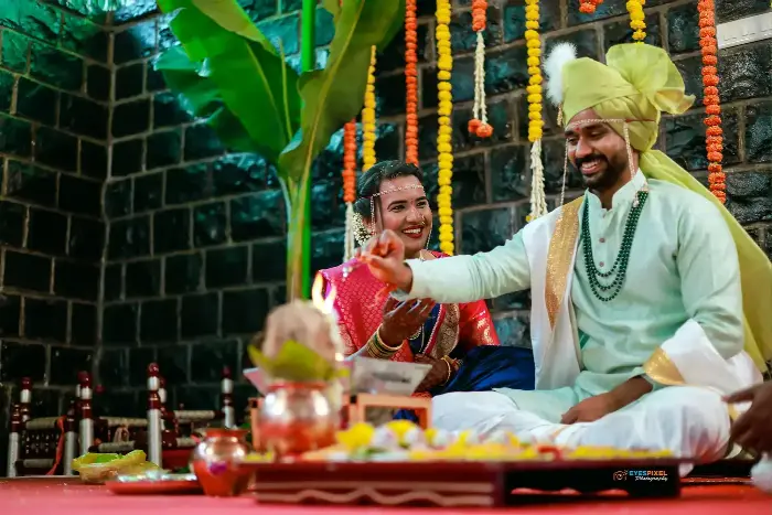Bride and groom seated at the ritual fire, the groom making an offering