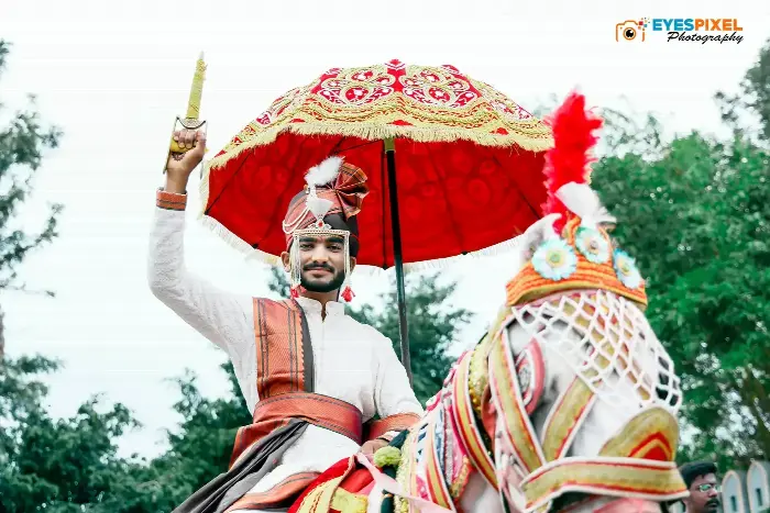 Groom on a decorated horse beneath a red and gold ceremonial umbrella