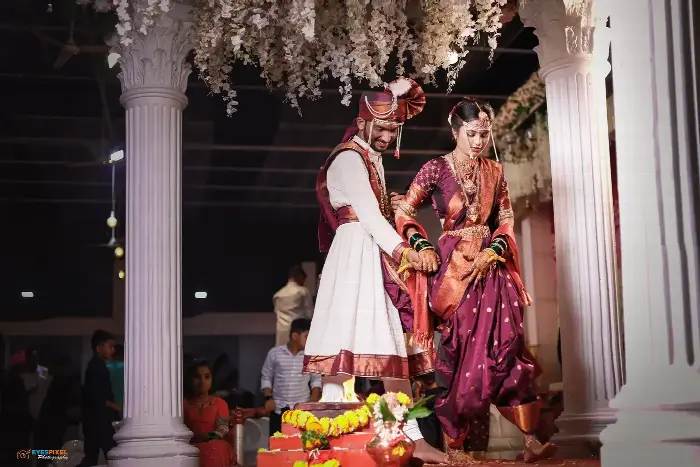 Bride and groom performing a ritual beneath a floral canopy between white pillars