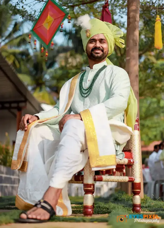 Groom in a green pheta seated on a decorated chair outdoors before the ceremony