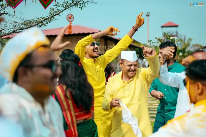 Guests in yellow kurtas dancing outdoors during the haldi celebration