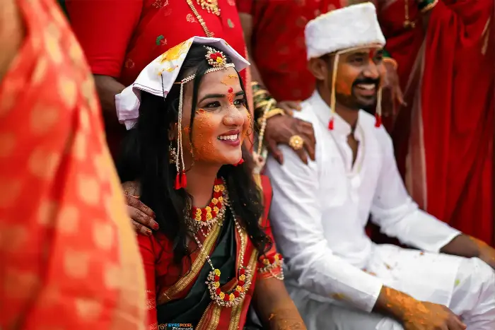 Bride smiling during the haldi ceremony, turmeric on her face, groom beside her