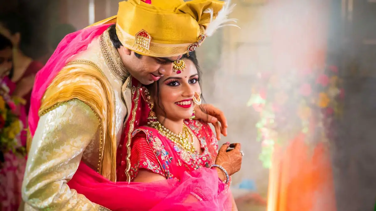Bride and groom in gold and pink smiling together during their wedding ceremony in Pune