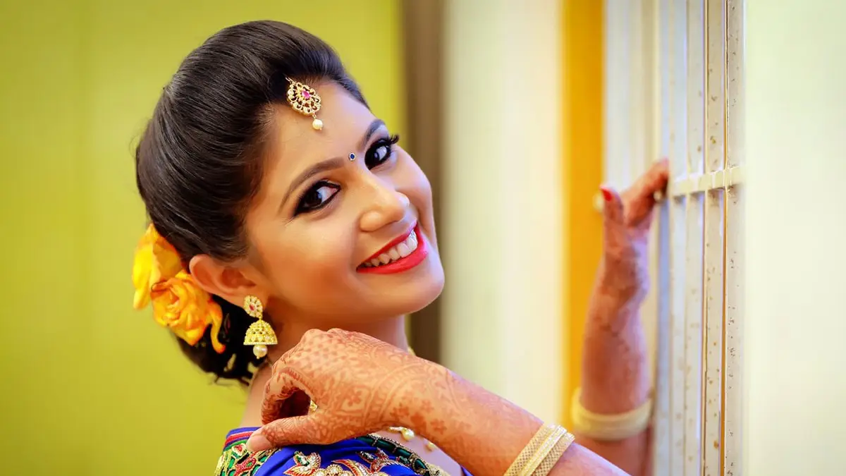 Bridal portrait, mehendi on her hands, resting against a doorway