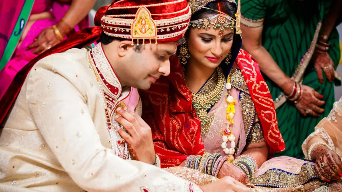 Bride and groom seated together during a wedding ritual, family close around them